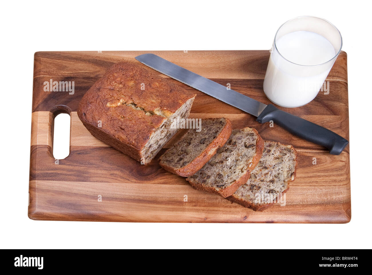 Pane a fette di banana pane alle noci su un tagliere di legno con un bicchiere di latte su bianco Foto Stock