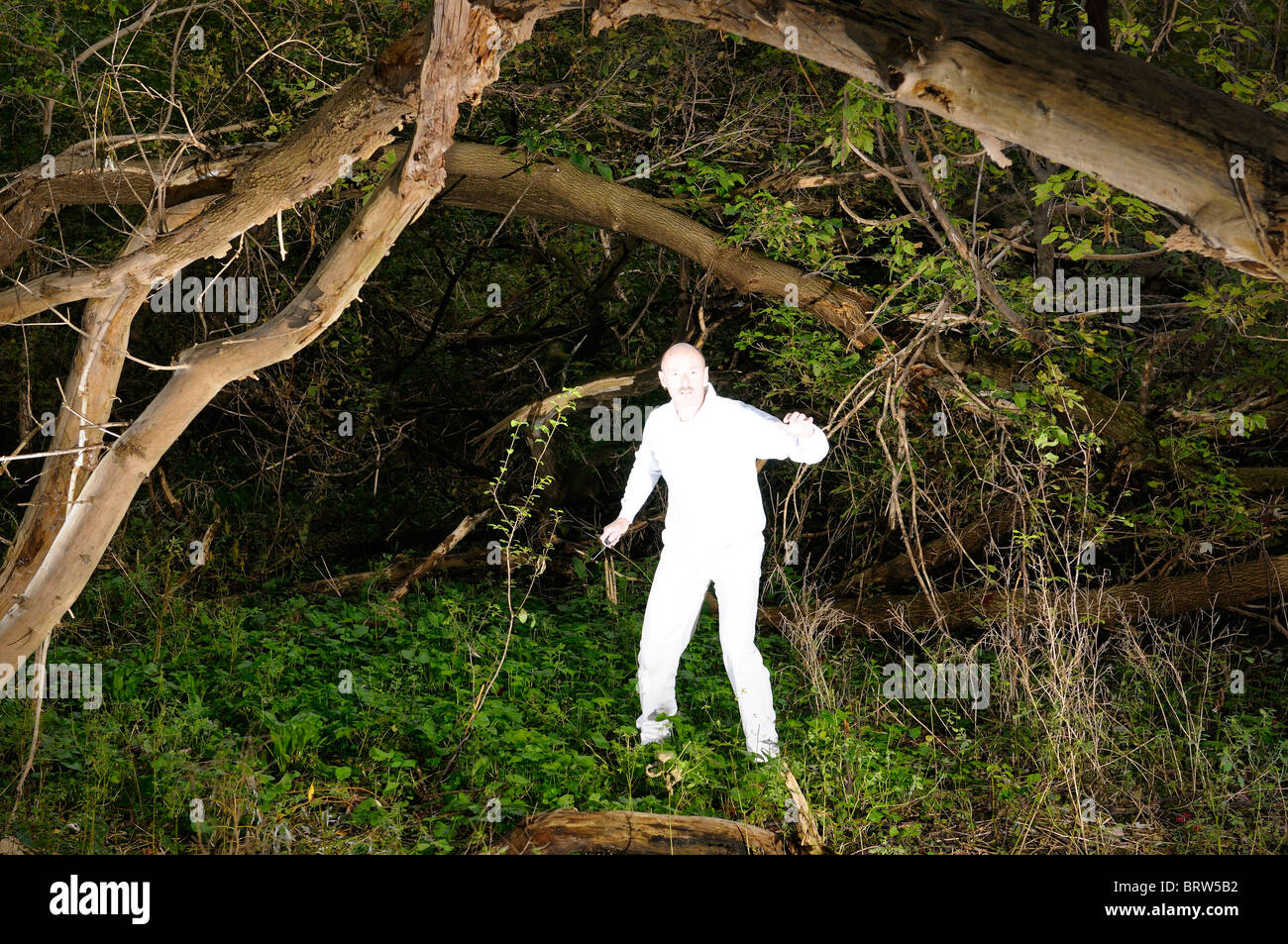 Spazio alieno invasore uomo incandescente in bianco puro con dispositivo elettronico catturati in una fitta foresta infestata da erbacce del pianeta terra Toronto Foto Stock