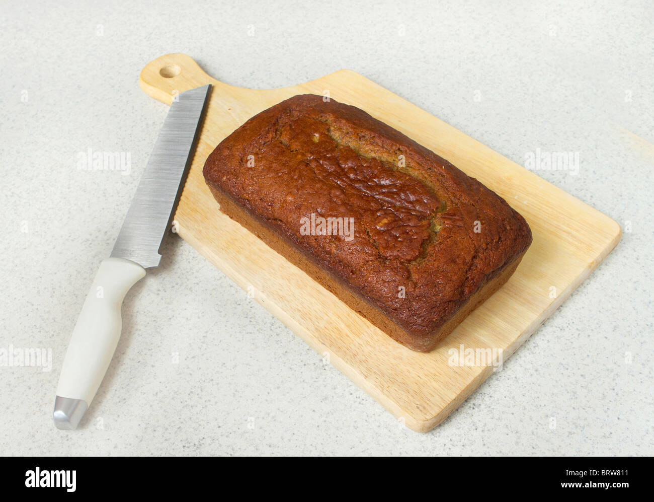 Una pagnotta di pane alla banana su un tagliere con coltello su un piano del banco Foto Stock