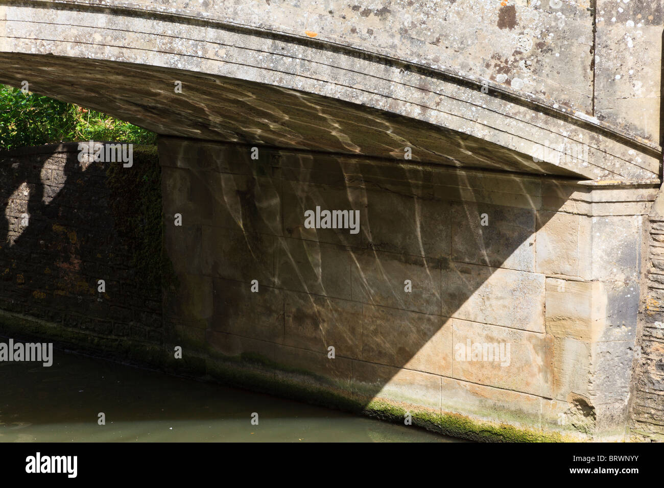 Increspature sul Fiume Tamigi brillare di luce sui modelli di conformazione arcuata del ponte di pietra a Iffley, Oxford, Oxfordshire, Regno Unito Foto Stock