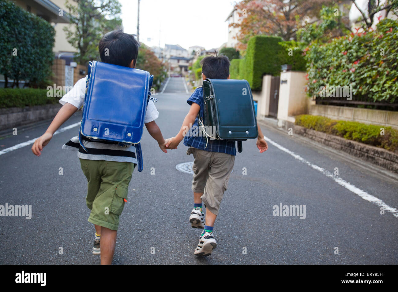 Ragazzi tenendo le mani e in esecuzione, Prefettura di Tokyo, Honshu, Giappone Foto Stock