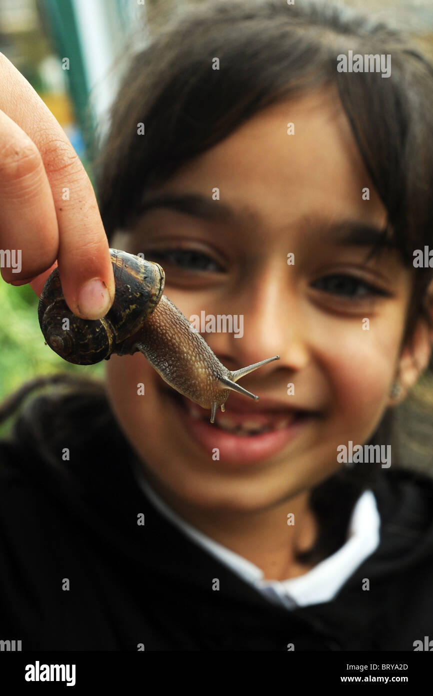 Un bambino studia un giardino va a passo di lumaca sollevandolo, come parte dell'esperienza di giardinaggio di visitare una città interna riparto, Bradford Foto Stock