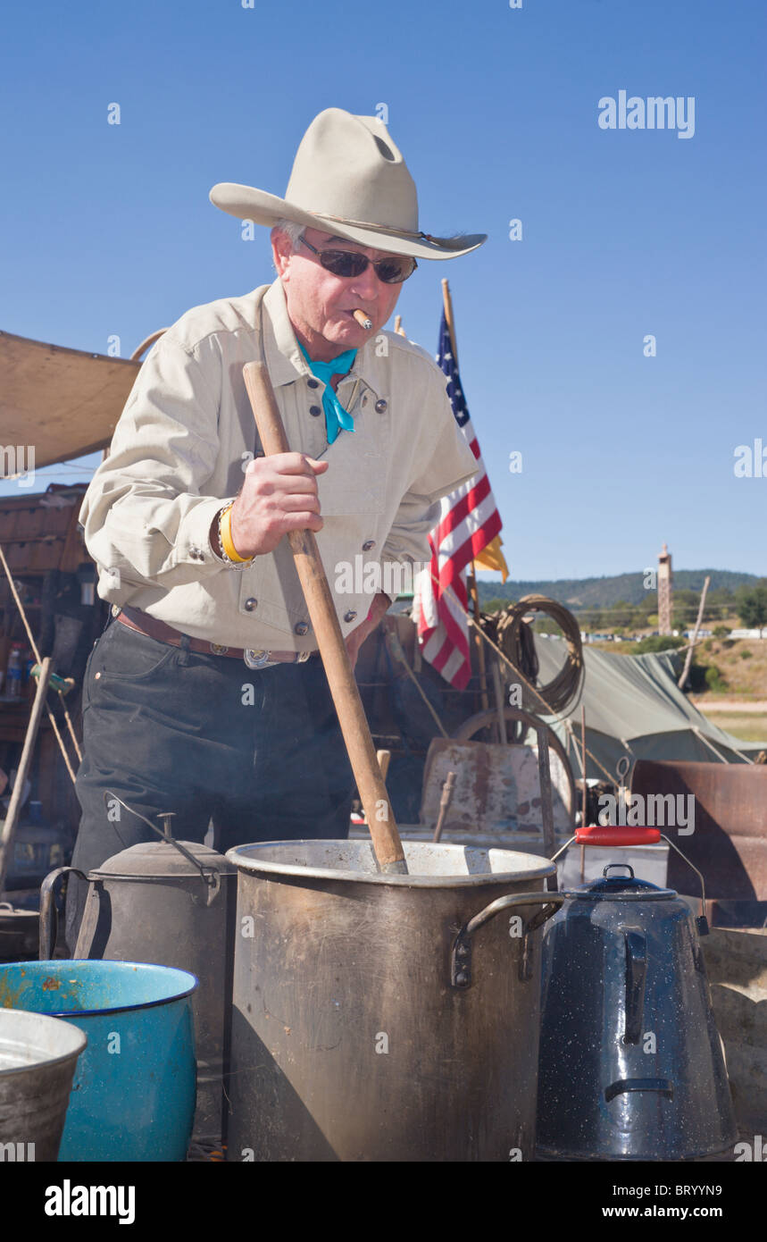 Il sigaro-fumatori cowboy suscita la pentola, presso il Lincoln County Cowboy Simposio e Chuck wagon Cook-Off, Ruidoso Downs, Nuovo Messico. Foto Stock