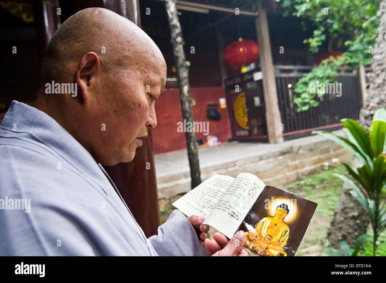 Un Cinese monaco buddista script per la lettura di un libro sacro. Foto Stock
