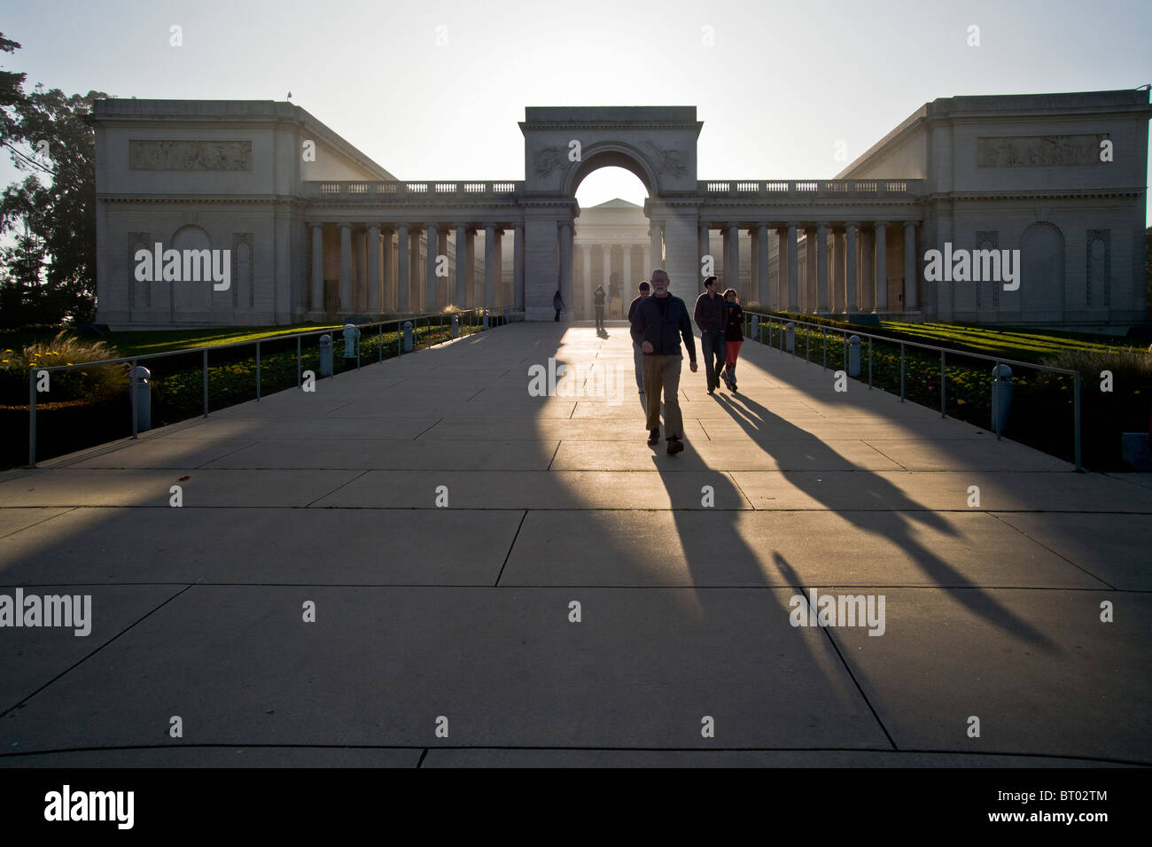 Pomeriggio di sole getta ombre lunghe di visitatori presso il fine art museum California Palace della Legione di Onore a San Francisco. Foto Stock