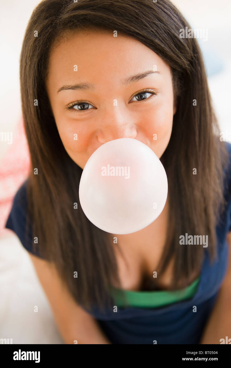 Close up di razza mista ragazza adolescente di soffiaggio con bubble gum Foto Stock
