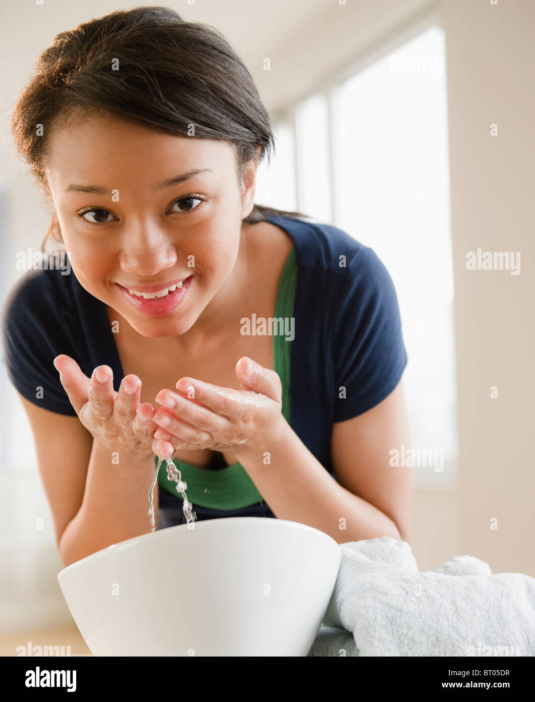 Sorridente razza mista ragazza adolescente faccia di lavaggio Foto Stock