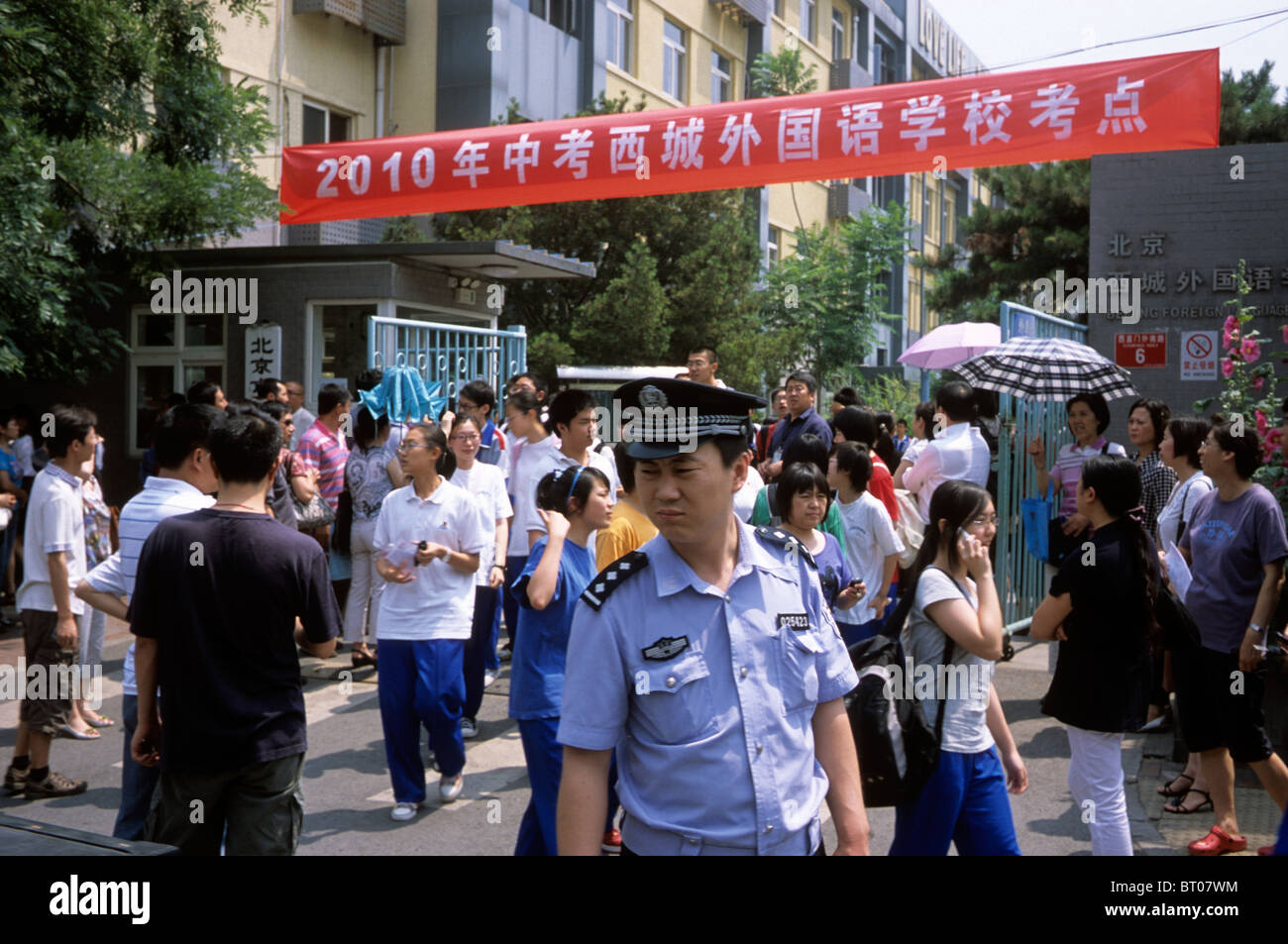 Un poliziotto di pattuglia mentre gli studenti lasciare una scuola dopo aver preso parte a senior high school esame di ammissione a Pechino in Cina. Foto Stock