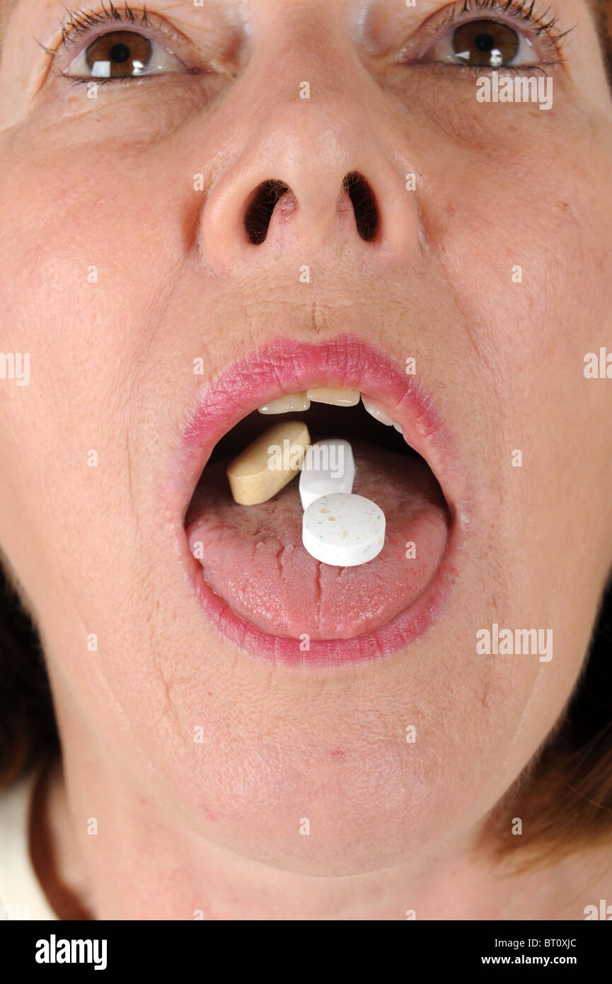 Donna di mezza età con vitamine sulla linguetta Foto Stock