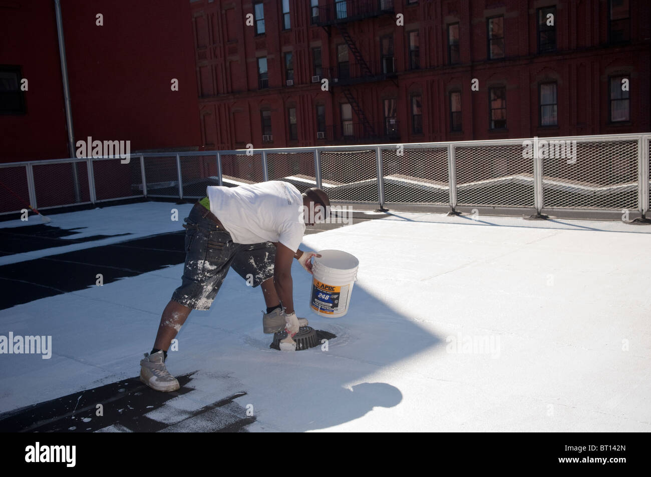 Volontari dipingere una scuola coolroof in Harlem in New York Foto Stock
