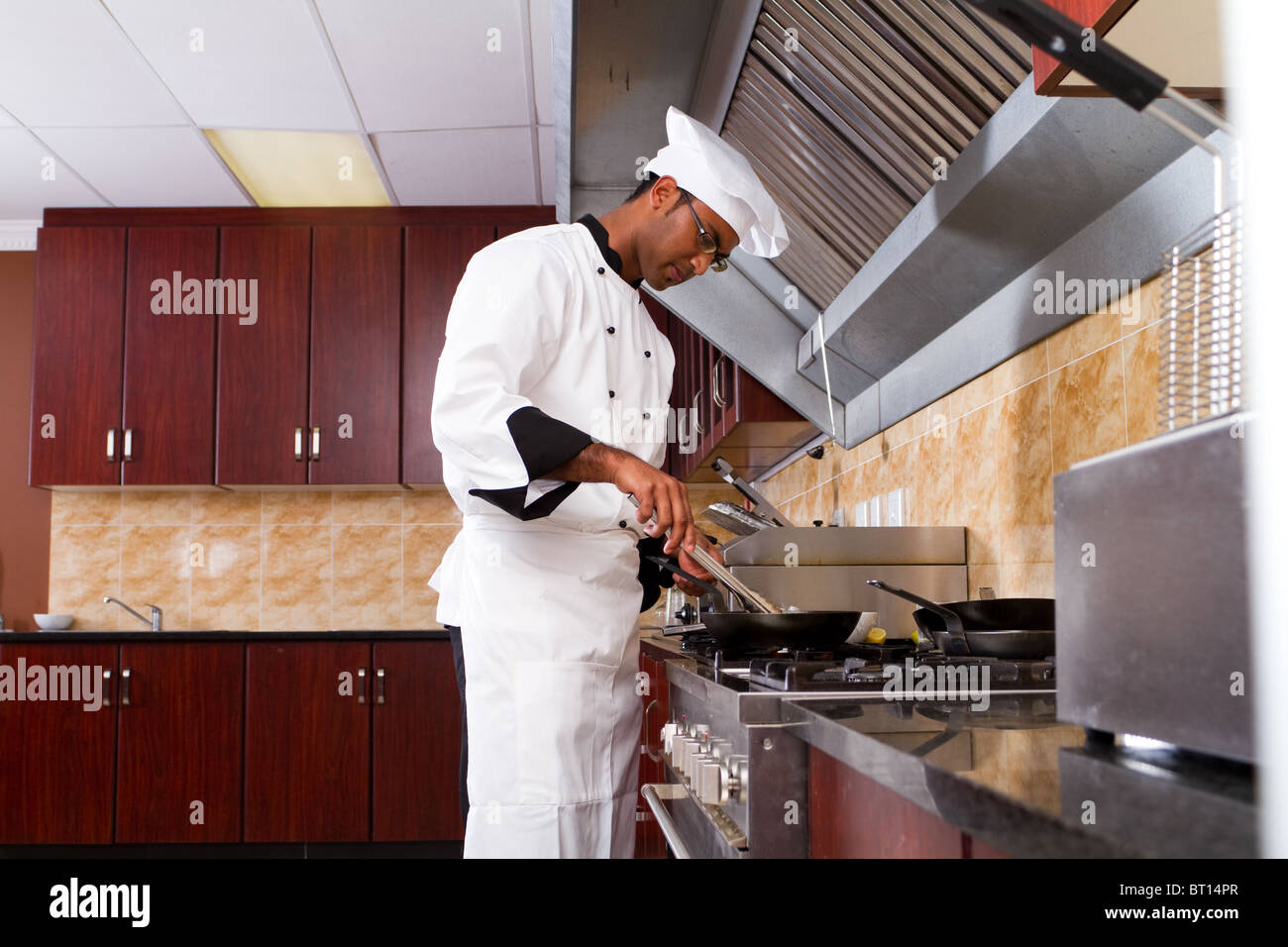 Giovane maschio professionale indiana la cucina dello chef in cucina commerciale Foto Stock