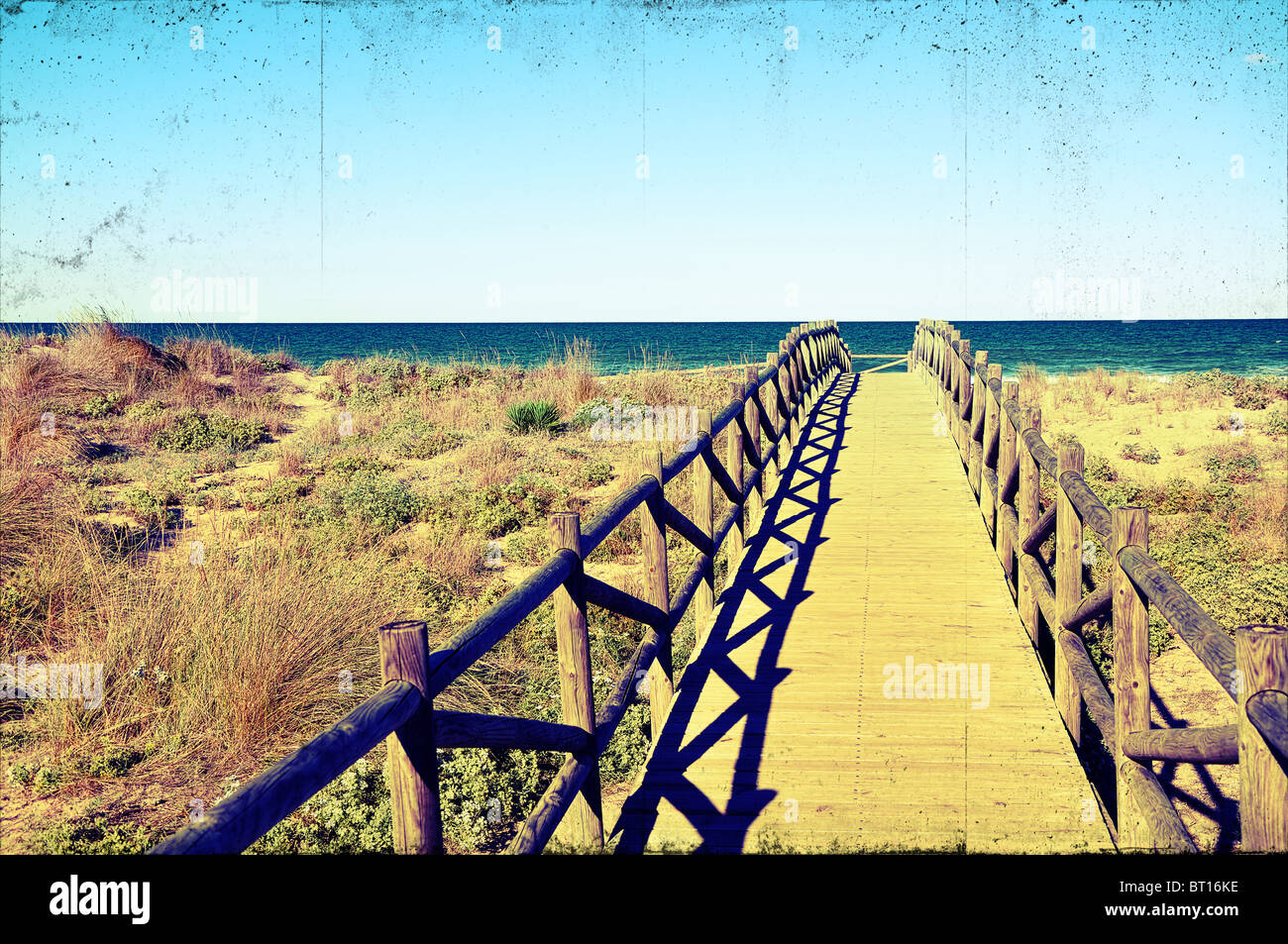 Ponte di legno sulla spiaggia con dune di un processo trasversale e effetto vigneting a guardare grungy e vecchio Foto Stock
