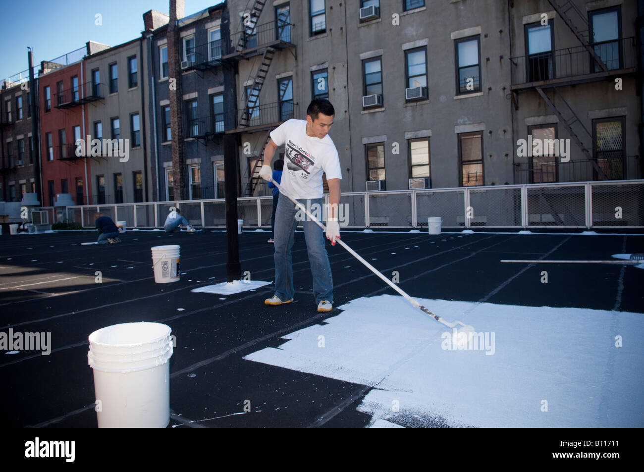 Volontari dipingere una scuola coolroof in Harlem in New York Foto Stock