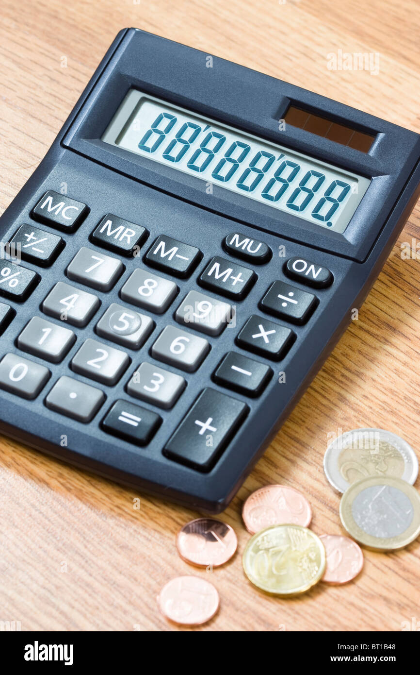 Calcolatrice nero con numeri sul display insieme ad alcune monete in euro sul tavolo Foto Stock