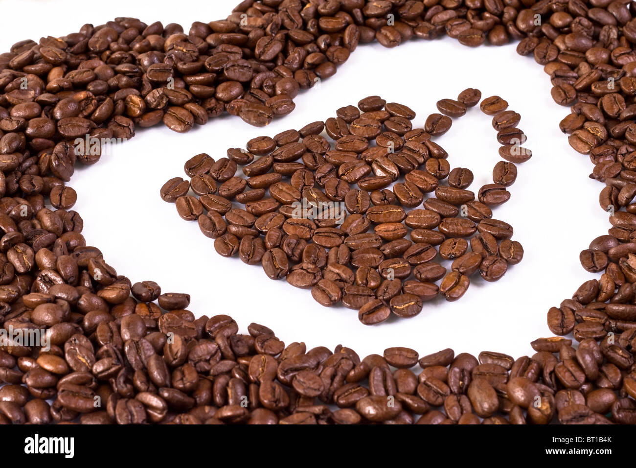 Tazza di caffè in chicchi di caffè circondati da una forma di cuore Foto Stock