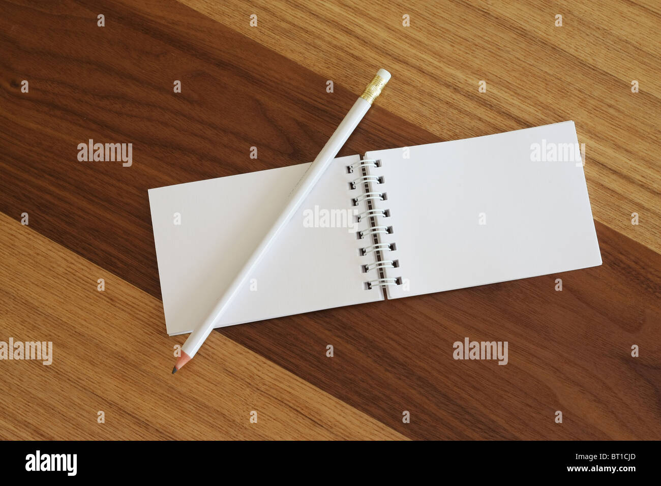 Vuoto bianco blocco note a spirale con una matita su una scrivania in legno. Foto Stock