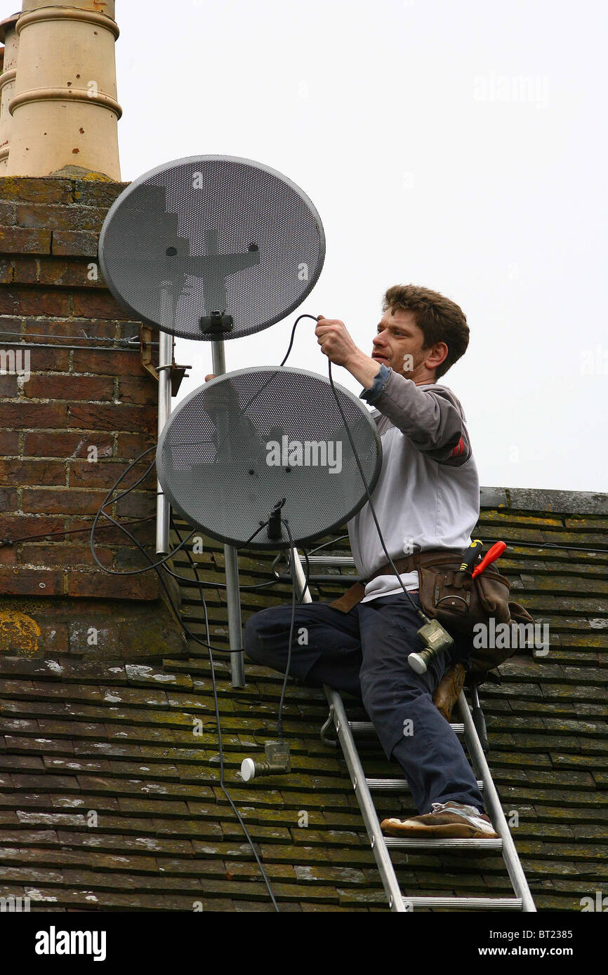 Un' Antenna e satellite engineer opera su un tetto. Foto di James Boardman Foto Stock