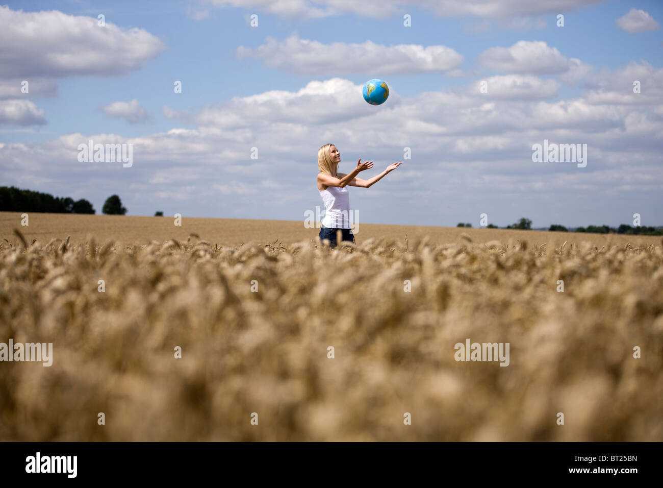 Una donna in piedi in un wheatfield, la cattura di un globo Foto Stock