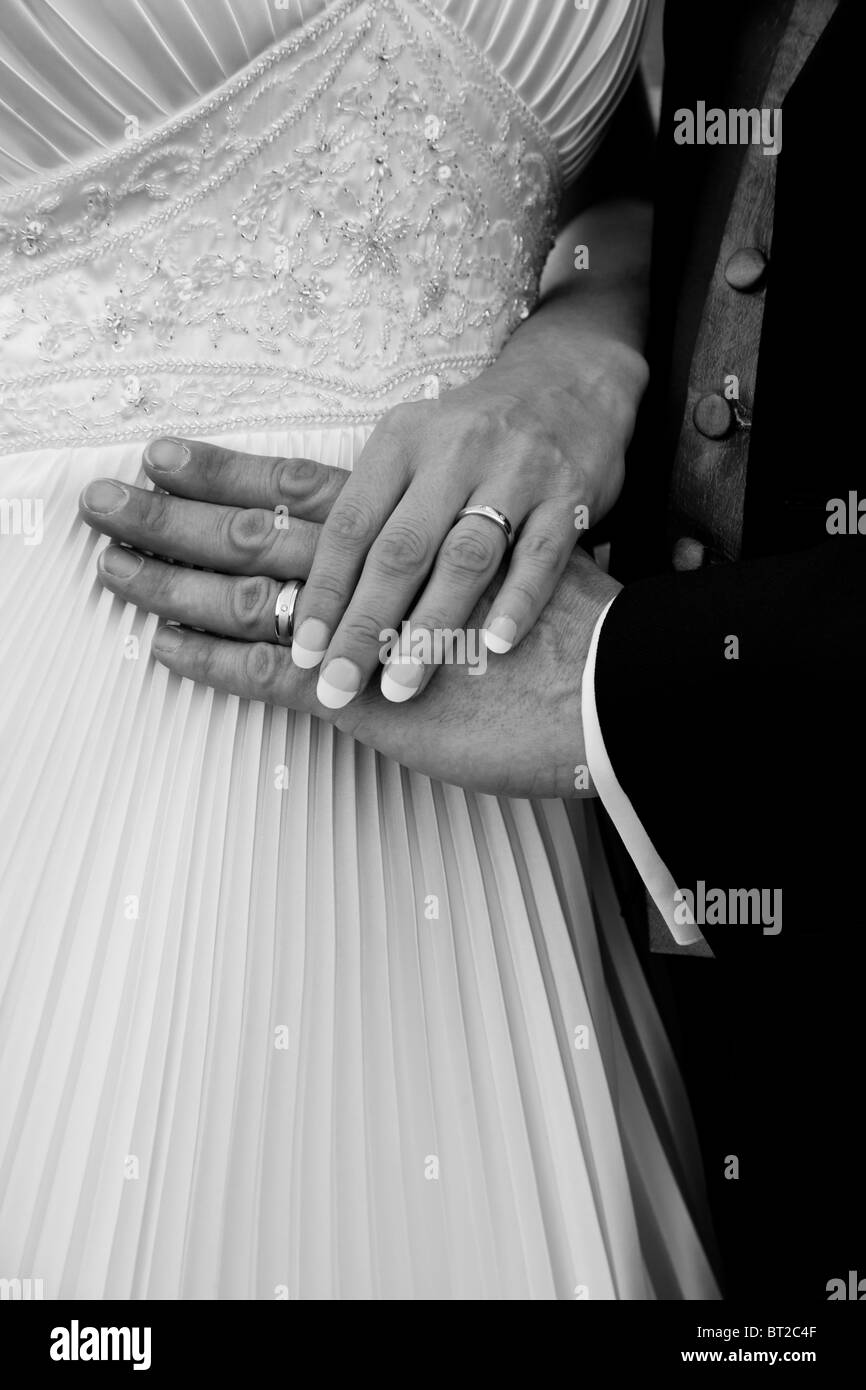 Un matrimonio giovane mostrare loro anelli contro le spose abito. Foto Stock