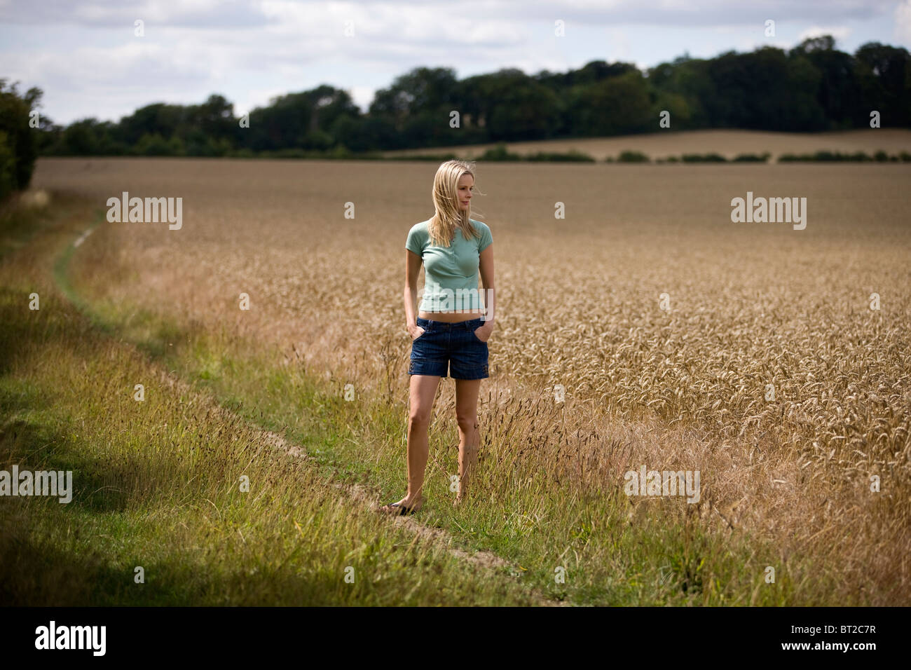 Una donna in piedi accanto a un wheatfield Foto Stock