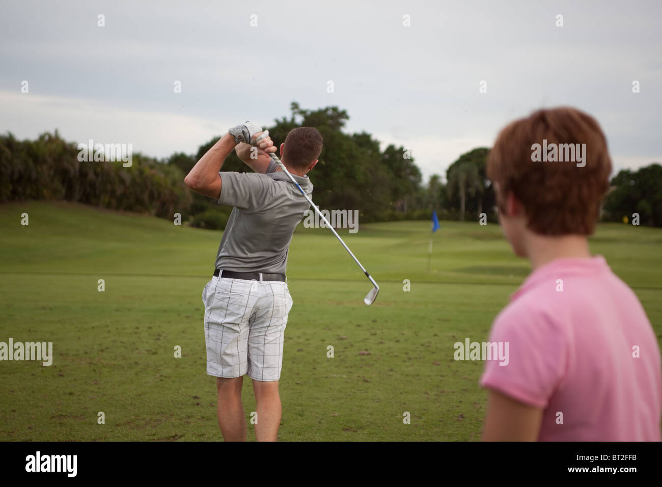 Golfista maschio colpisce la palla mentre donna guarda. Foto Stock