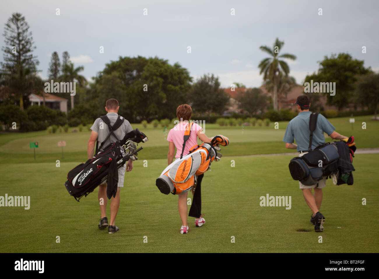 Tre i golfisti a piedi verso il loro prossimo colpo. Foto Stock