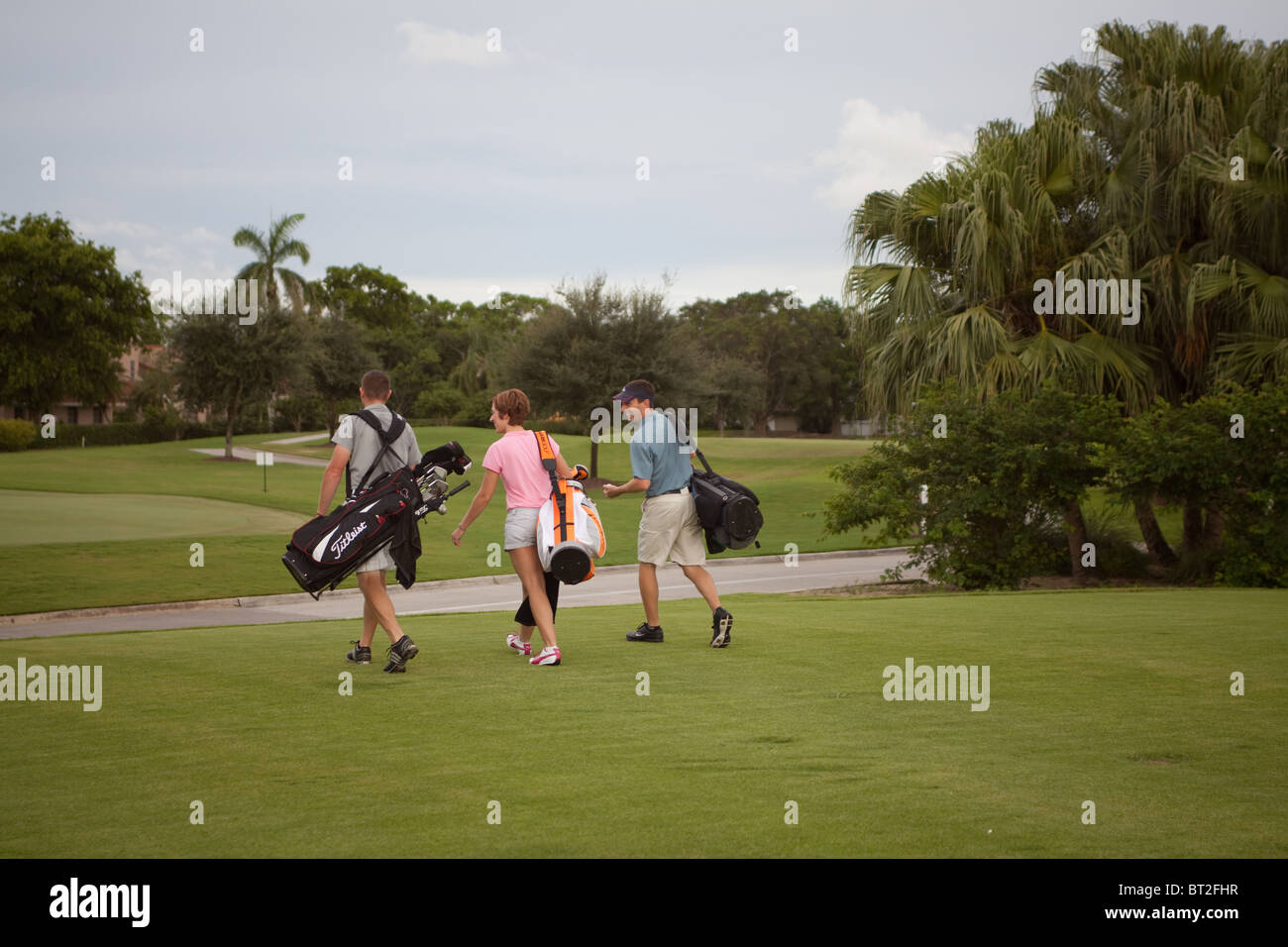 Tre i golfisti a piedi verso il loro prossimo colpo Foto Stock