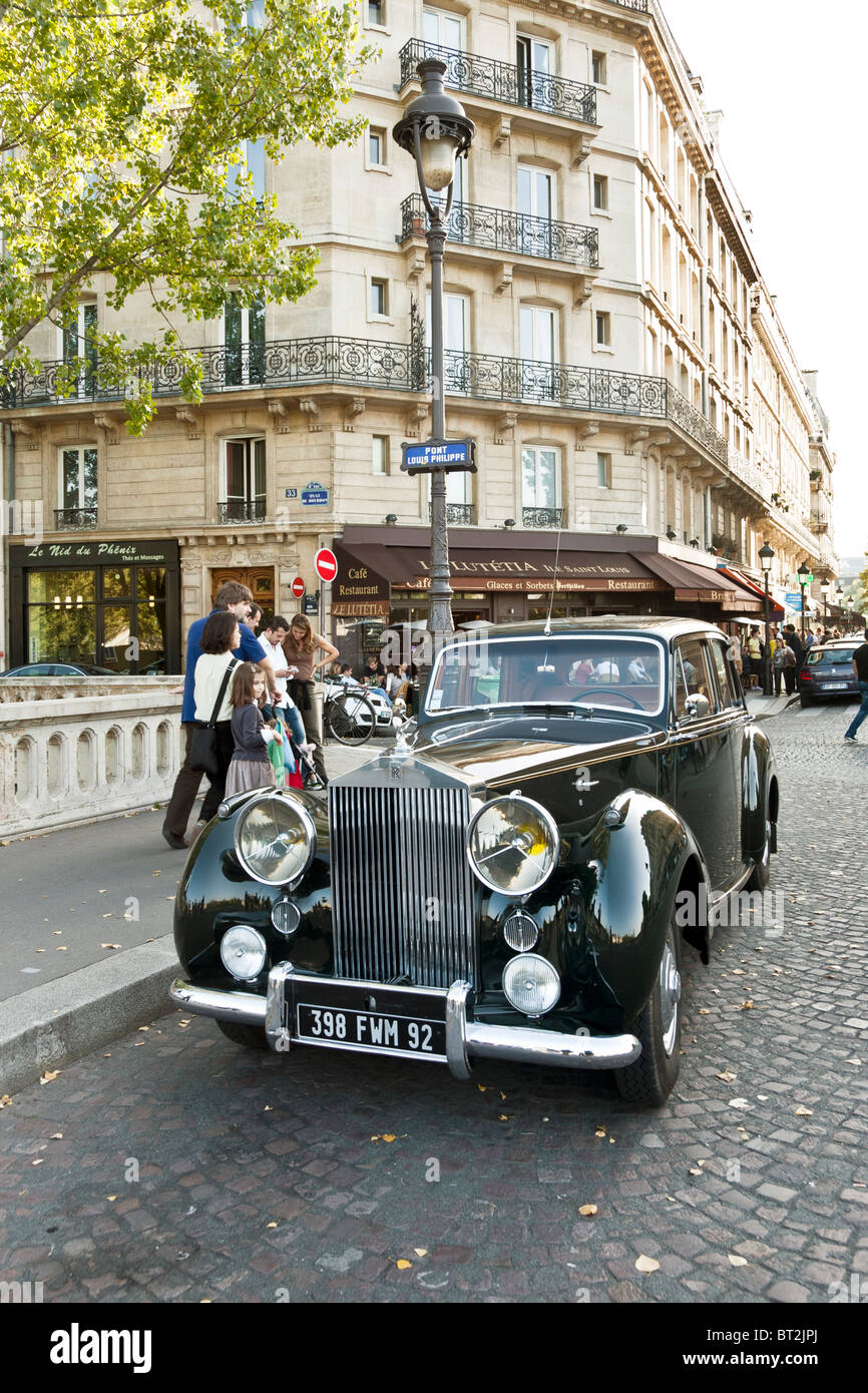 Weekend strada parigina la vita continua intorno al magnifico luccicanti vecchio Rolls Royce parcheggiata sul Pont Louis Philippe a Parigi Foto Stock