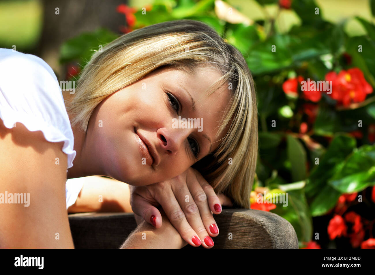 Bionda ritratto femminile con fiori in background. Foto Stock