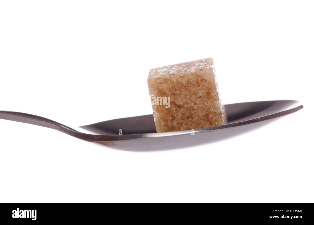 Uno zucchero bruno cubo su un cucchiaino di ritaglio Foto Stock