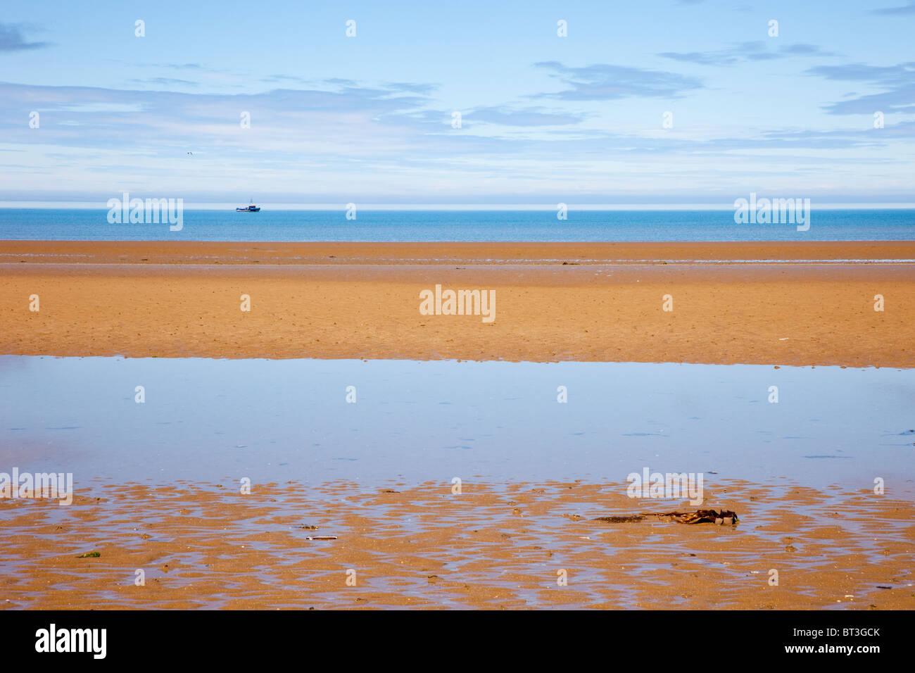 Generico Red Wharf Bay con piscina di marea sulla spiaggia di sabbia con la bassa marea e barca offshore nell incontaminato mare blu. Llanddona, Isola di Anglesey, Galles del Nord, Regno Unito Foto Stock