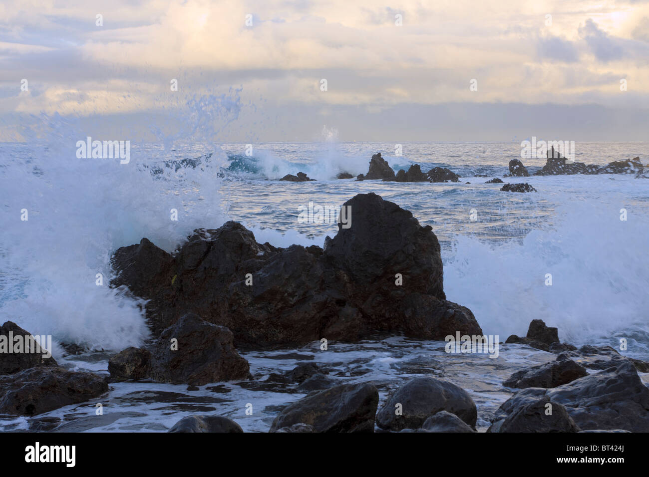 Le onde rompono sulle rocce all'alba sulla costa vicino a Playa San Juan Tenerife Canarie Spagna Europa Foto Stock