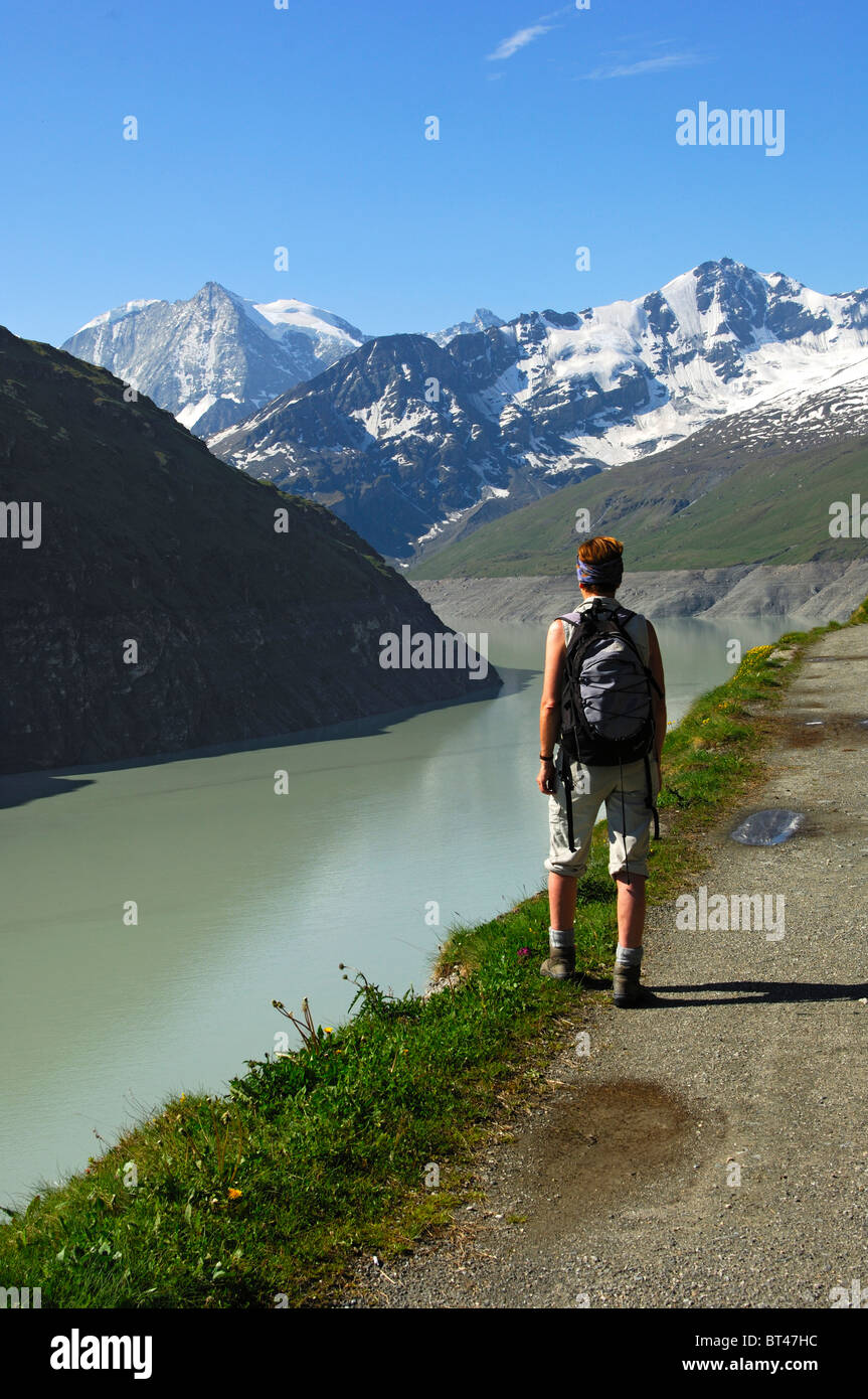 Escursionista presso il lago di storage Lac des Dix con Mt. Mont Blanc de Cheilon nel retro, Val d'Herens valley, Vallese, Svizzera Foto Stock