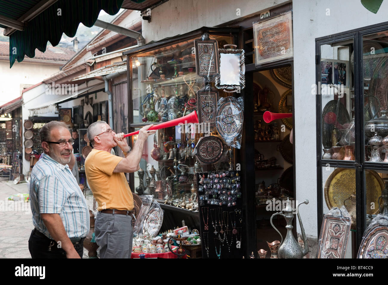 Commercianti soffiare le loro corna per segnalare la fine del giorno di negoziazione sulla strada Kazandžiluk Sarajevo, il posto per acquistare souvenir in rame. Foto Stock