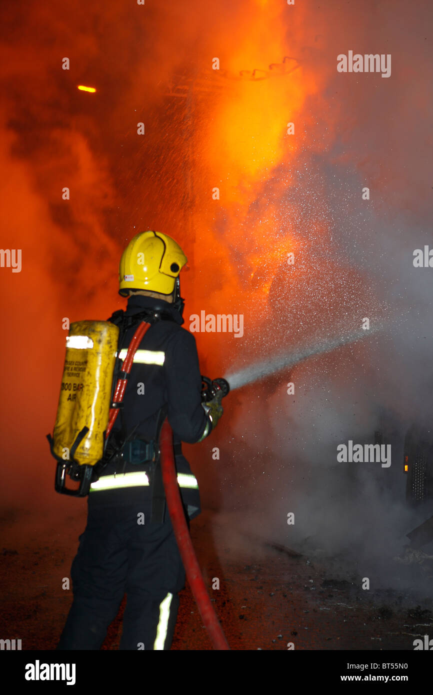 Firefighter affrontare un camion fuoco di notte Foto Stock