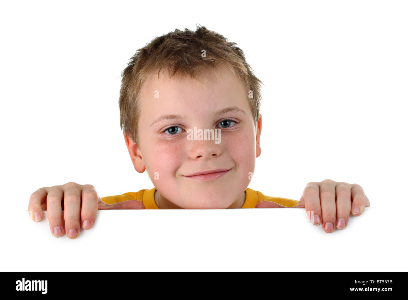Piccolo Ragazzo che guarda fuori da una lavagna vuota sorridente isolato su bianco Foto Stock