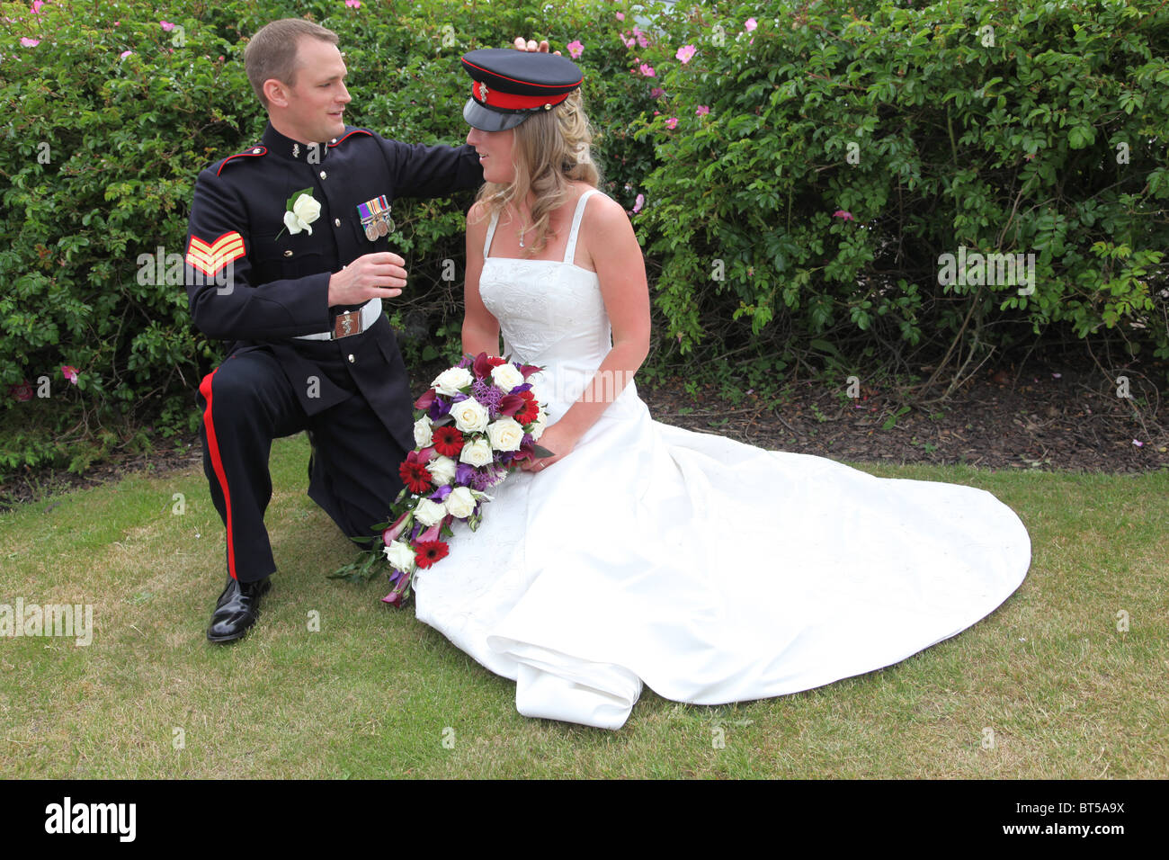Sposi in posa con fiori e cappello militare, lo sposo in uniforme di un  esercito britannico il sergente Foto stock - Alamy