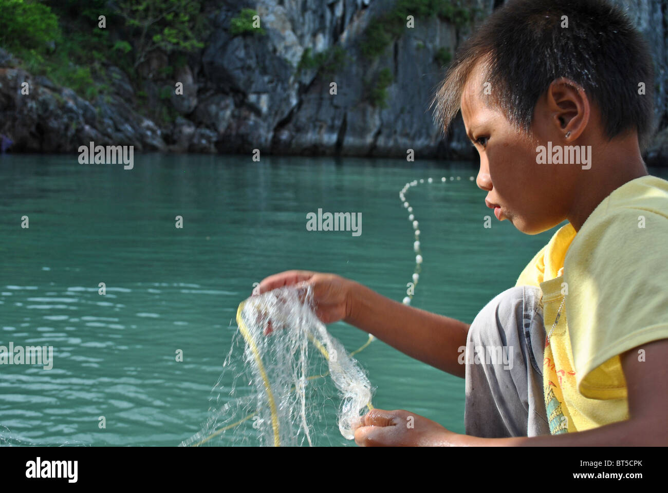 Bambino la pesca nella baia di Ha Long, Vietnam Foto Stock