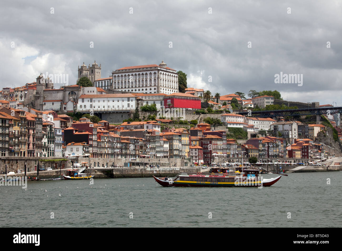 Vista del porto di Oporto attraverso il fiume Douro e vino porto pescherecci sotto un cielo tempestoso Foto Stock