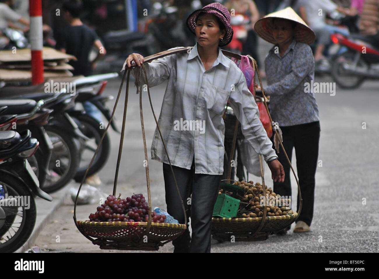 Le donne che trasportano cesti di frutta ad Hanoi, Vietnam Foto Stock