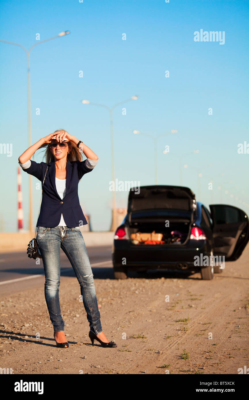 Giovane biondo con un broken auto sulla strada. Foto Stock