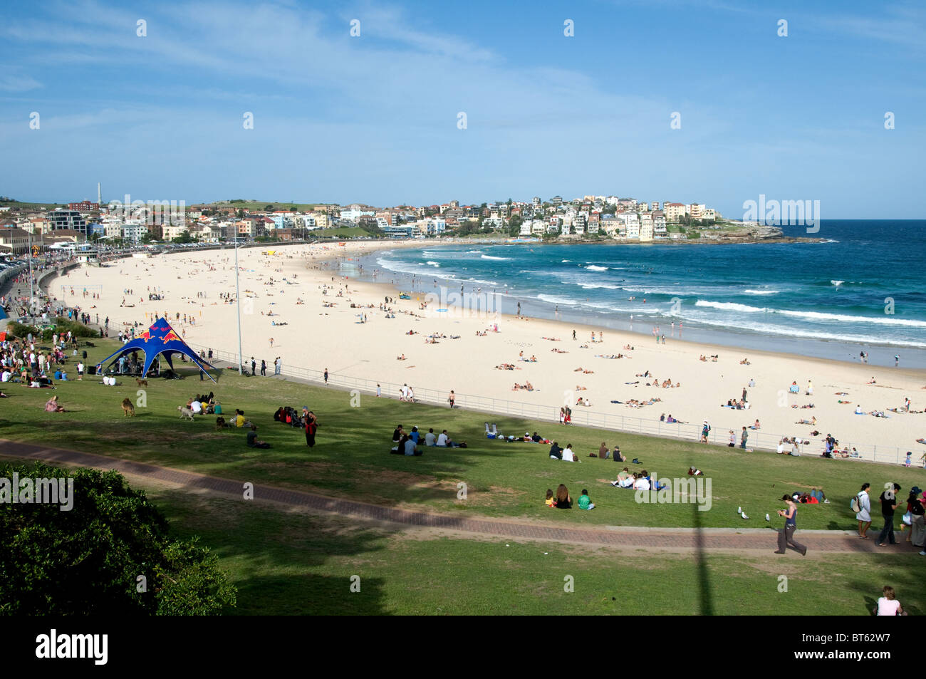 Bondi Beach Sydney Australia aussie surf surfer wave blue sea board a piedi grandi muta giornata soleggiata cielo blu bagni di sole sabbia Foto Stock