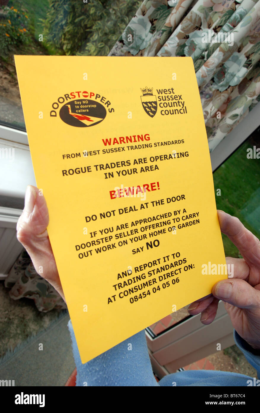 Donna anziana la lettura di un messaggio di avviso opuscolo informativo circa i commercianti disonesti & venditori a domicilio Foto Stock