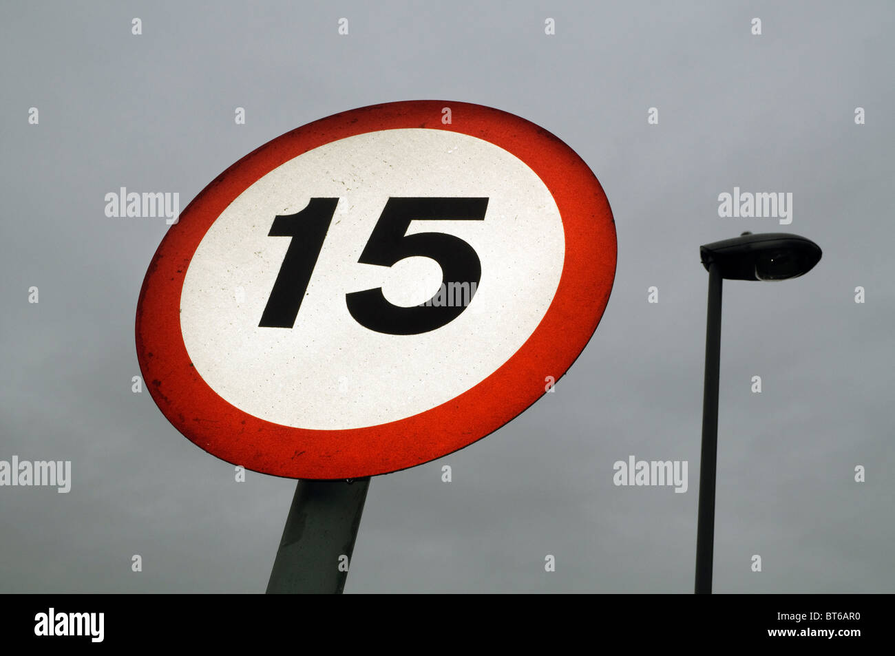 A 15 km/h il limite massimo di velocità segno di traffico contro un nuvoloso cielo grigio . Foto Stock