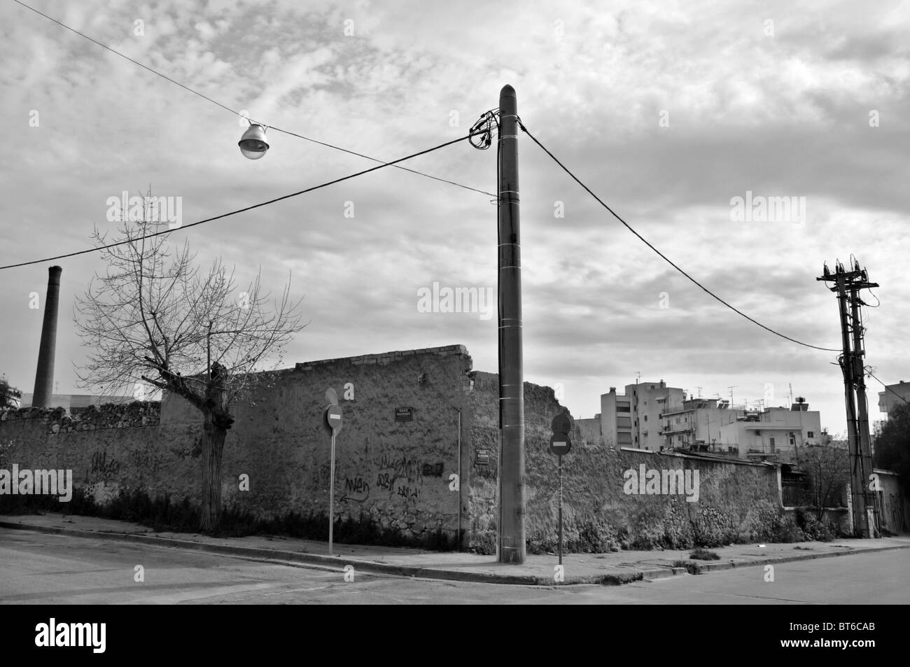 Sgretolamento parete in fabbrica e vuoto per le strade delle città. In bianco e nero. Foto Stock