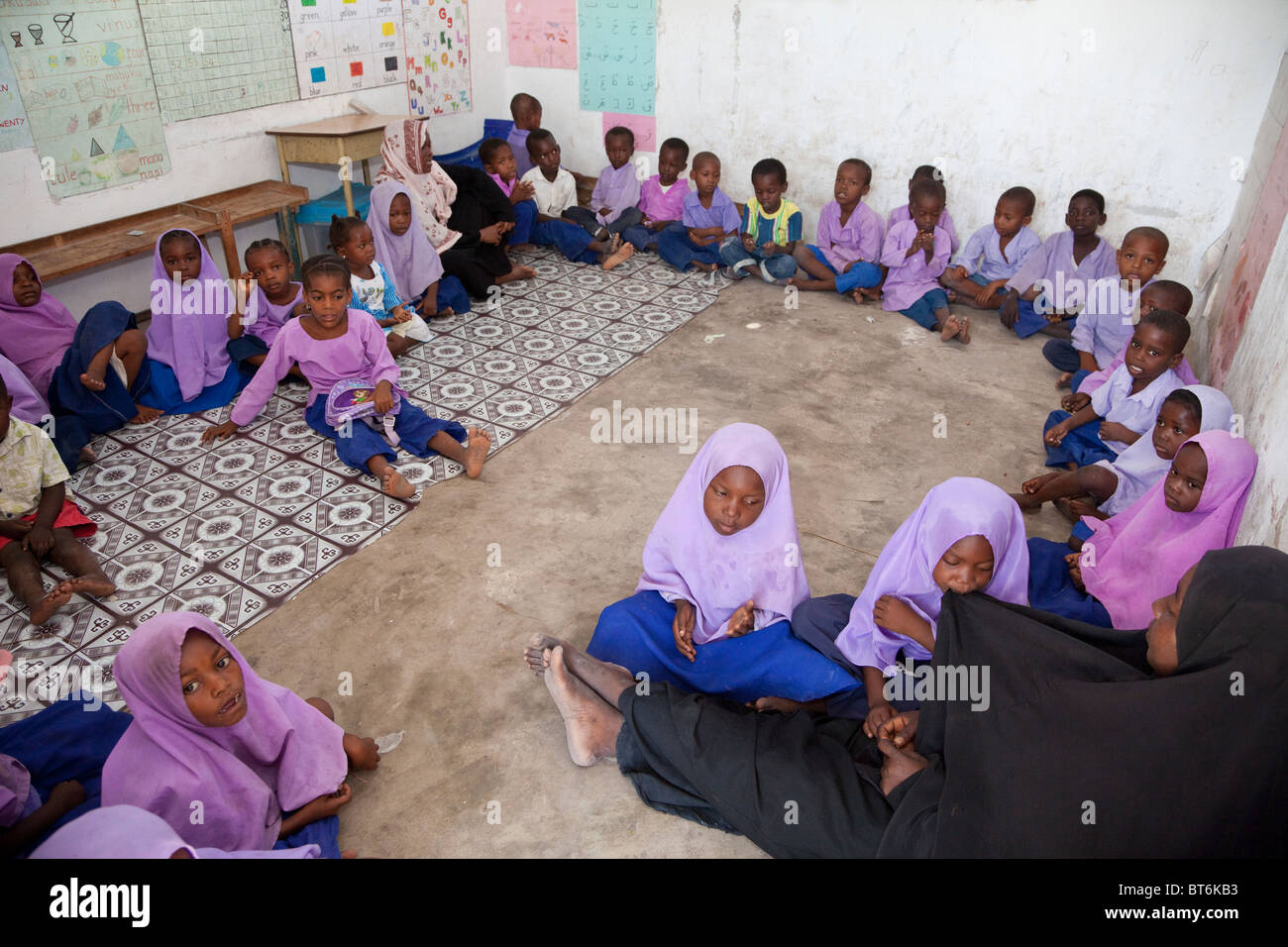 Jambiani, Zanzibar, Tanzania. La scuola primaria aula e scolari. Gli studenti seduti sul pavimento; la scuola non ha alcun mobili. Foto Stock