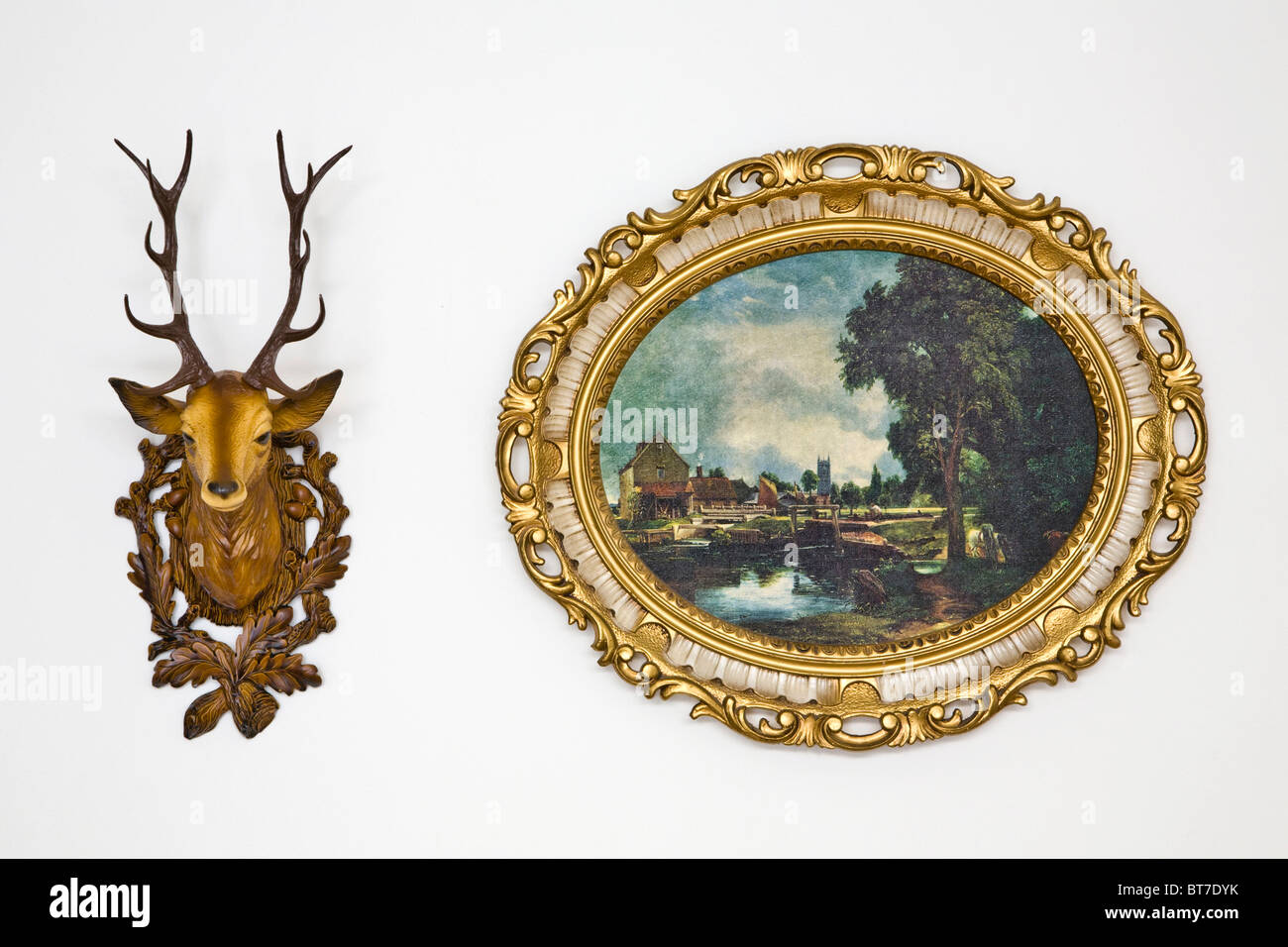 Plastica testa di cervo e un kitschy ovale, picture frame con un motivo del paesaggio Foto Stock