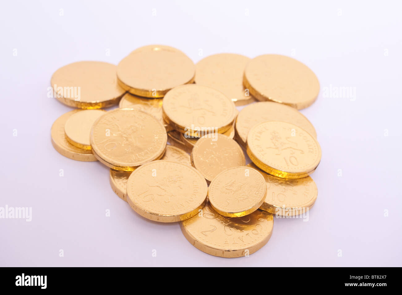 Un close up foto di alcuni oro monete di cioccolato contro uno sfondo bianco Foto Stock