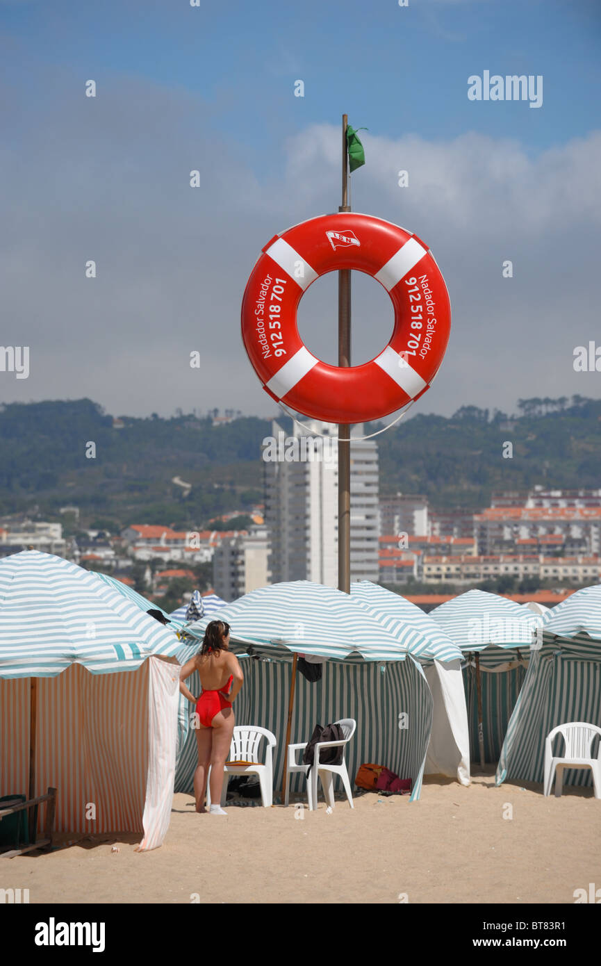 Woman in Red costume da bagno, bandiera verde e benedizione anello spiaggia striato tende Foto Stock