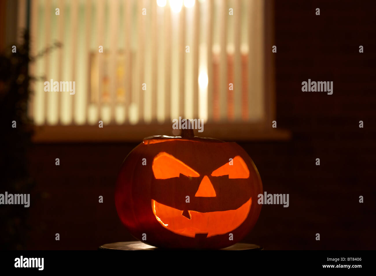 Illuminata la zucca di halloween jack-o-lantern al di fuori della finestra di una casa per allontanare gli spiriti maligni Foto Stock
